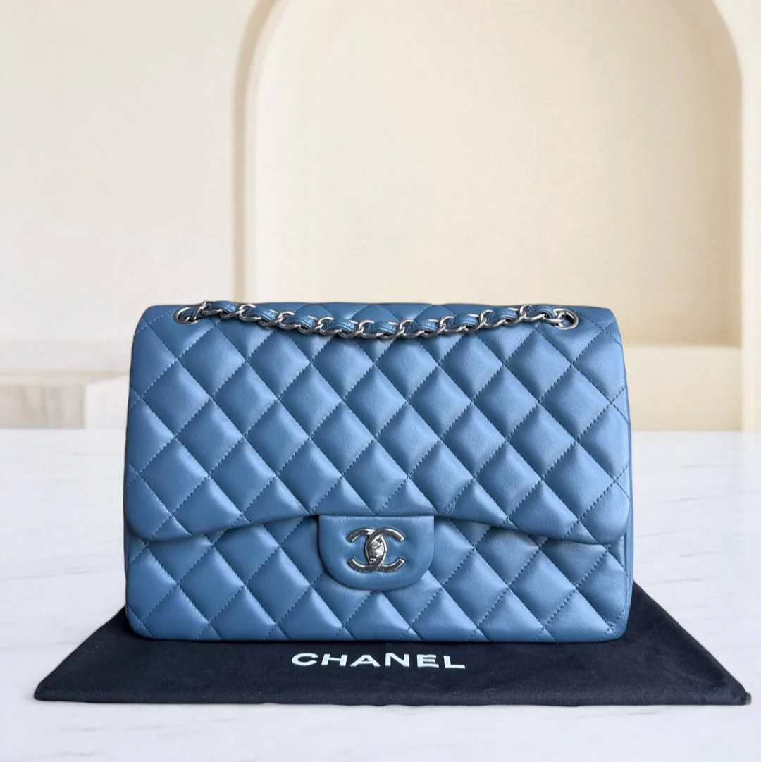 Blue quilted Chanel handbag on a black mat with a white background