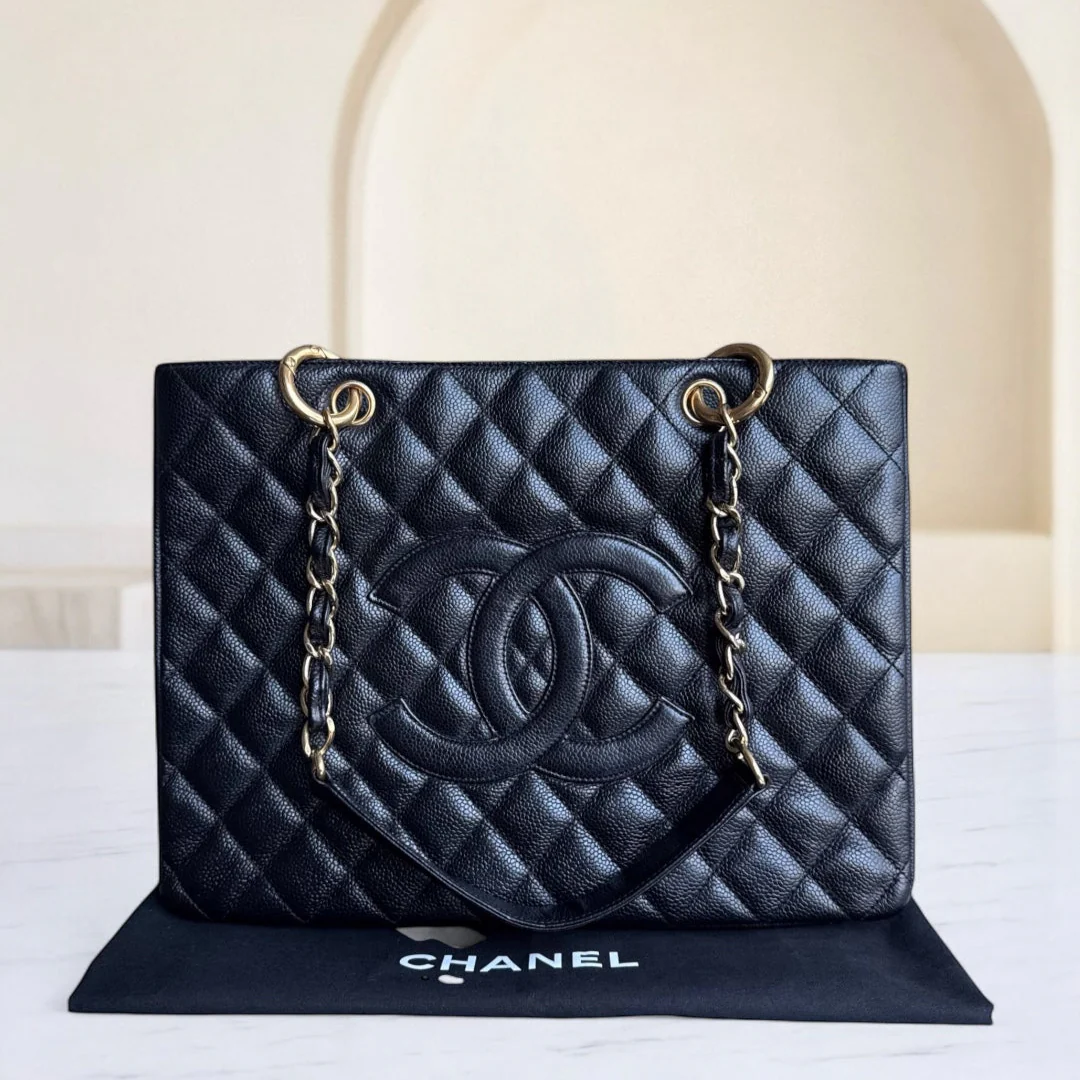 Black quilted Chanel handbag with gold chain on a white background