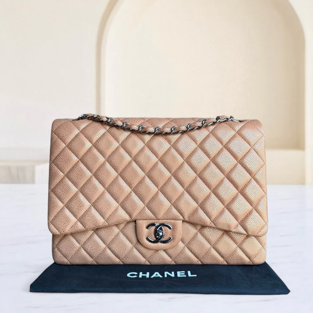 Beige quilted Chanel handbag on a white surface with a blurred background