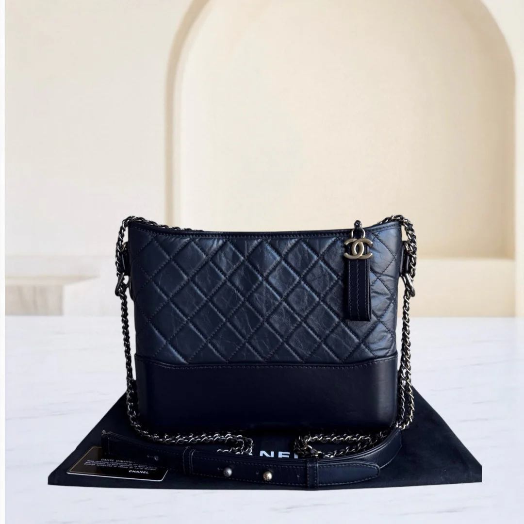 Black quilted handbag with chain detail on a white surface