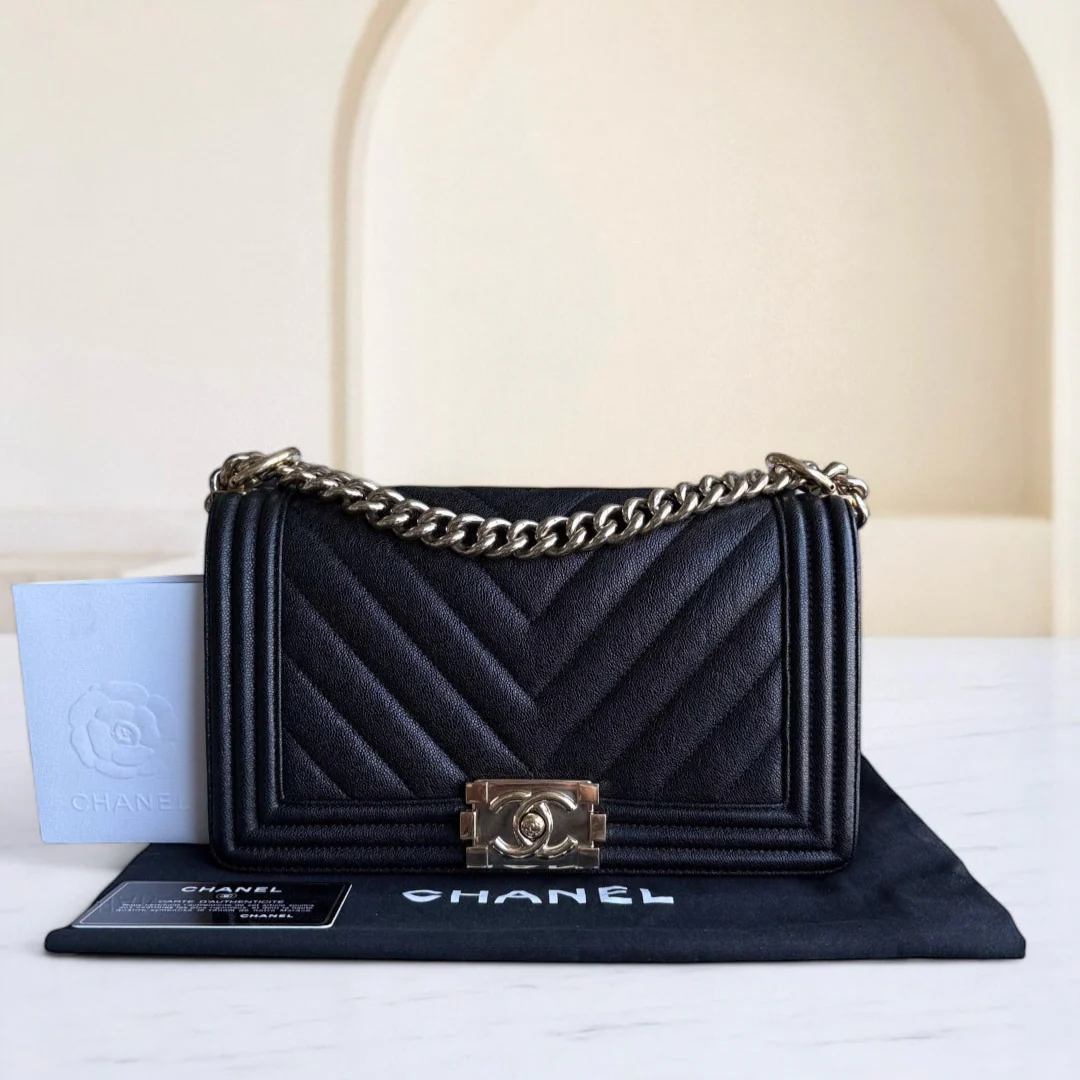 Black Chanel handbag with gold chain on a white surface