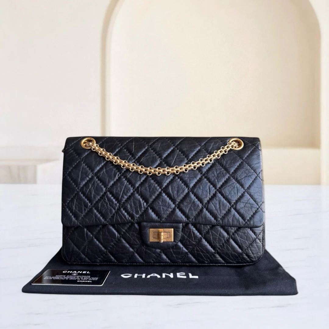 Black quilted Chanel handbag with gold chain on a white surface