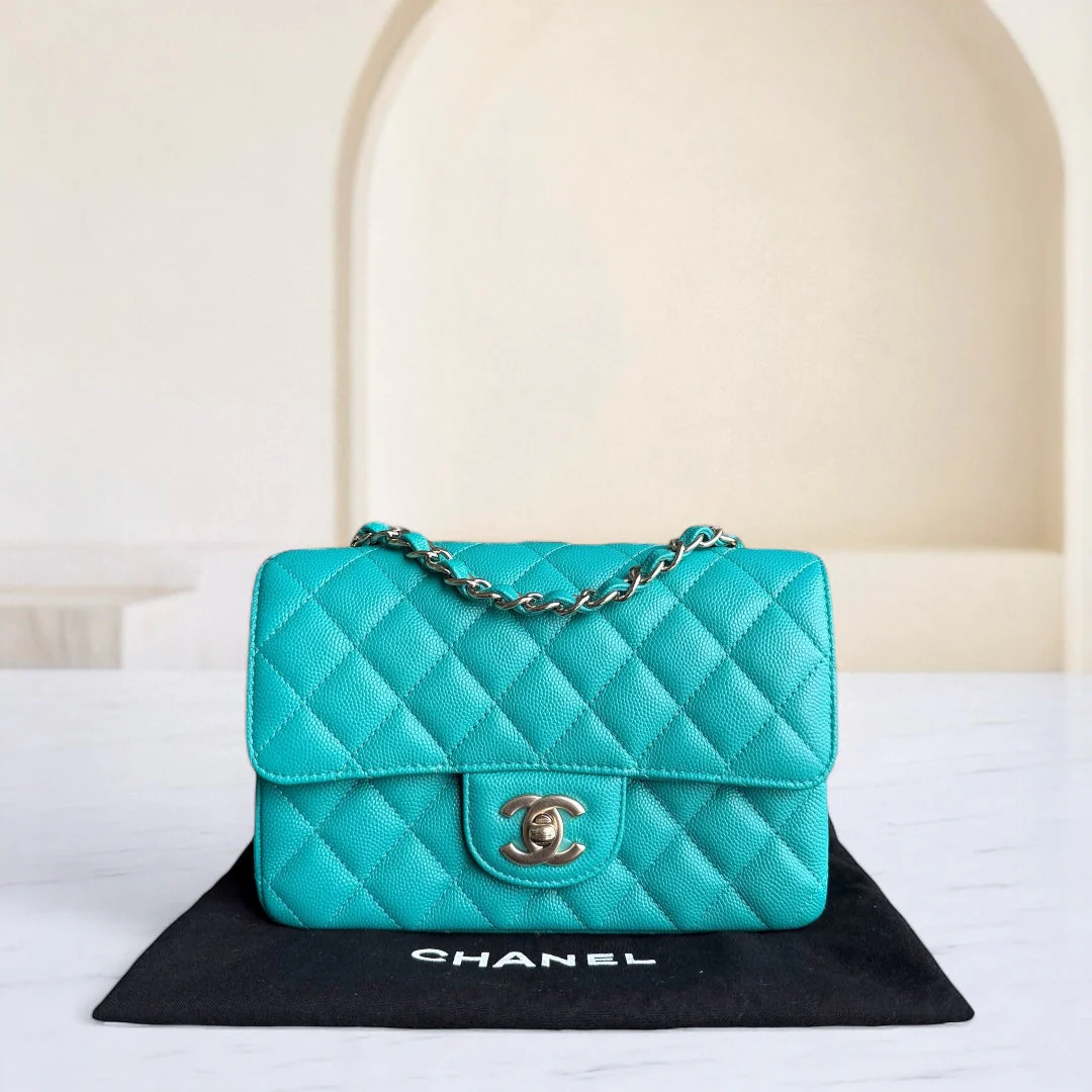 Turquoise quilted Chanel handbag on a black mat with a white background