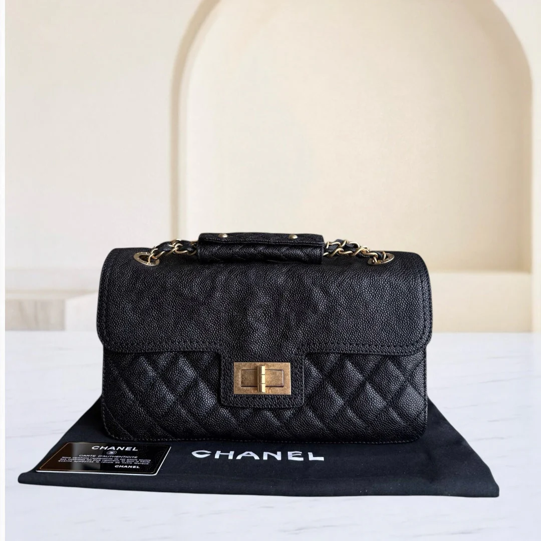 Black quilted Chanel handbag on a white surface with a blurred background