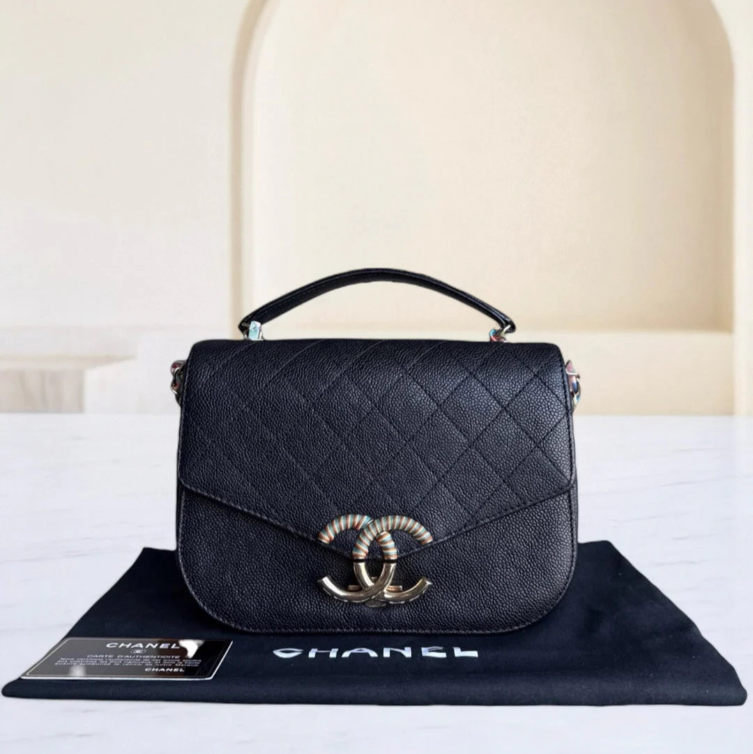 Black quilted Chanel handbag on a branded mat with a neutral background