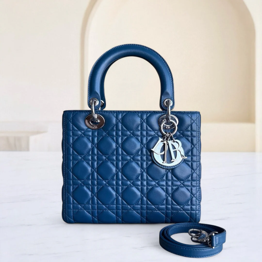 Blue quilted handbag with a brand logo on a white surface