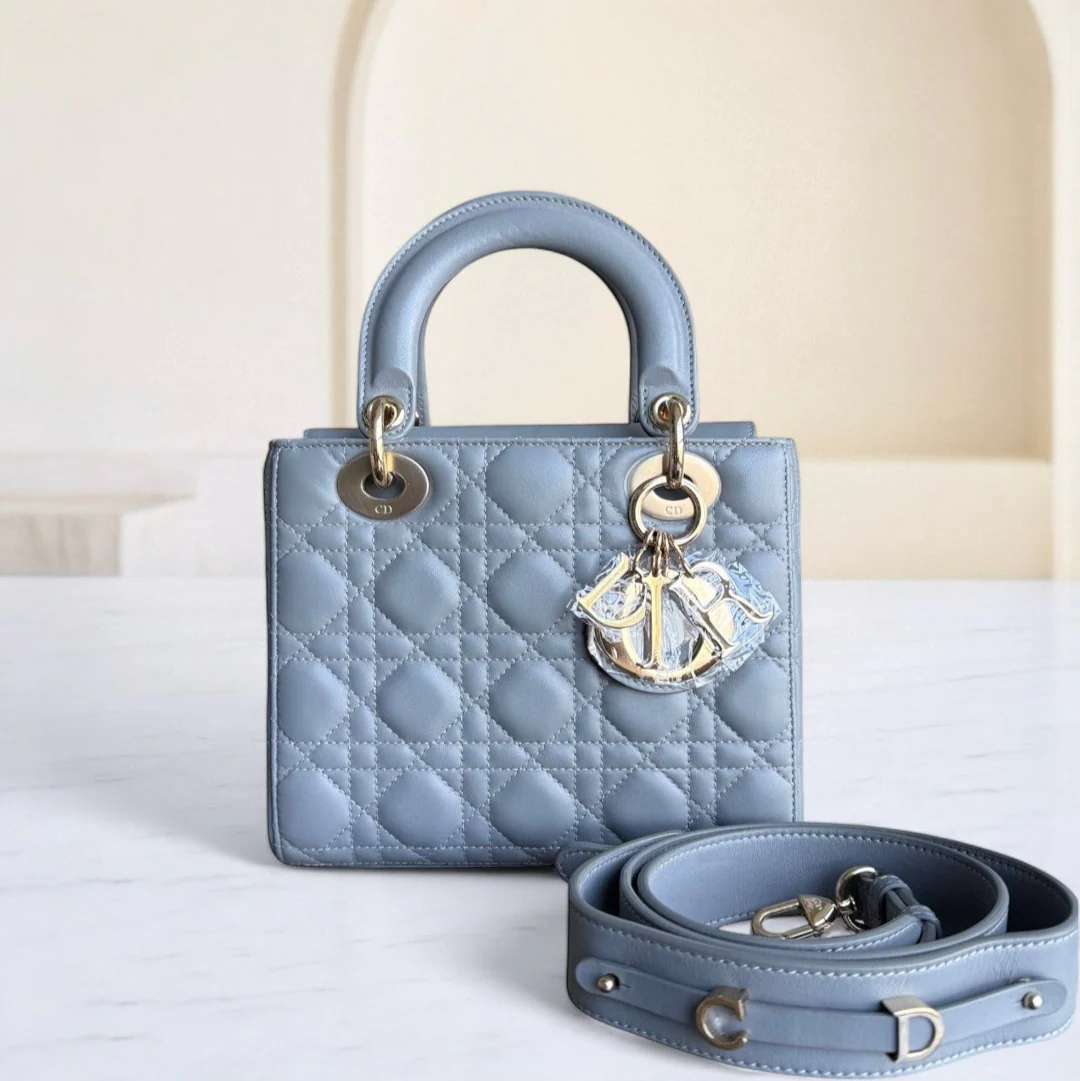 Blue quilted handbag with gold hardware on a white surface