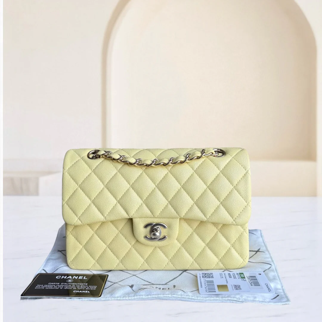 Light yellow quilted handbag with gold chain on a white surface