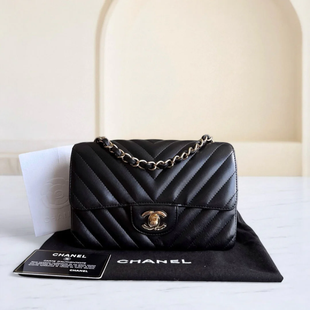 Black Chanel handbag on a white surface with a beige arch in the background