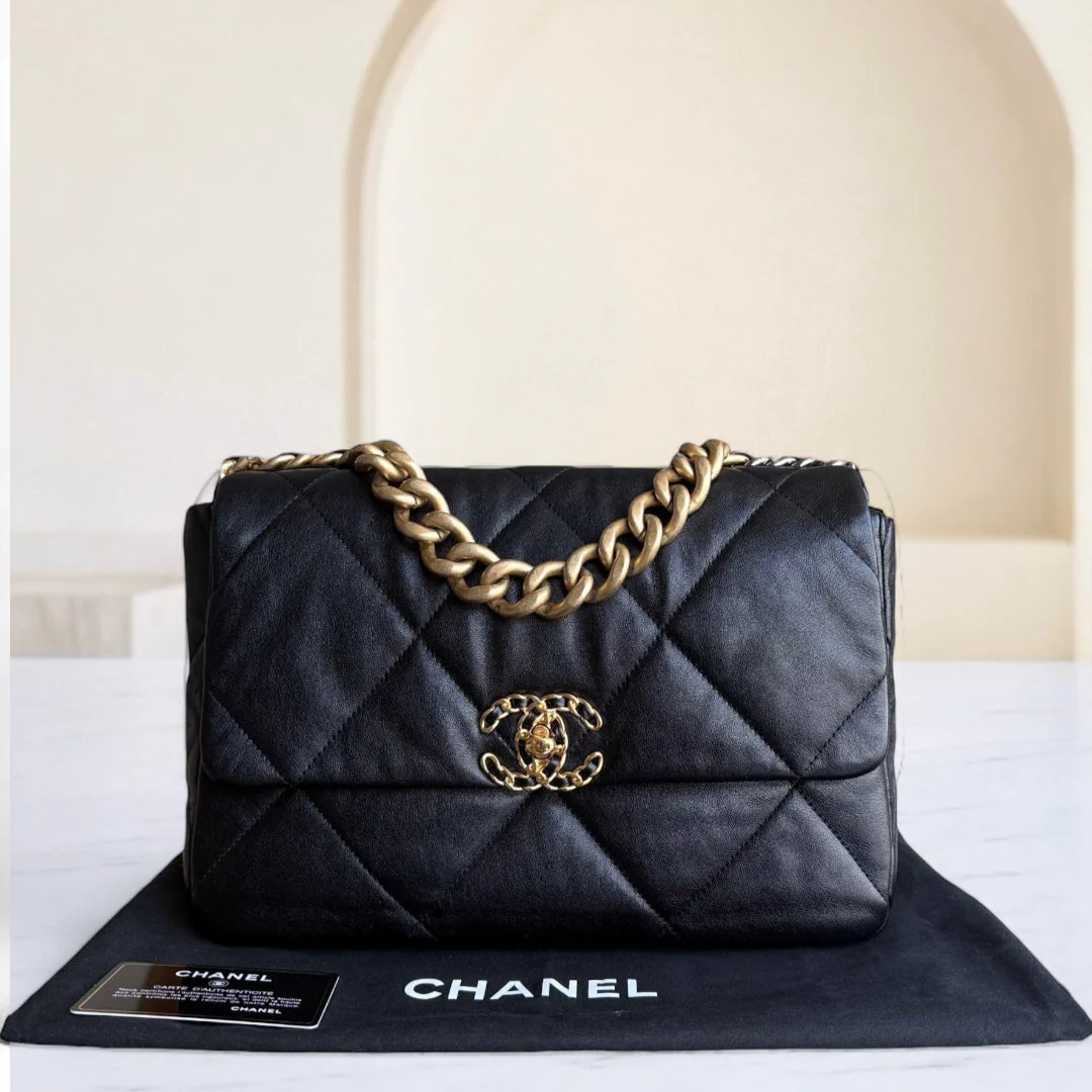 Black quilted Chanel handbag with gold chain on a white surface