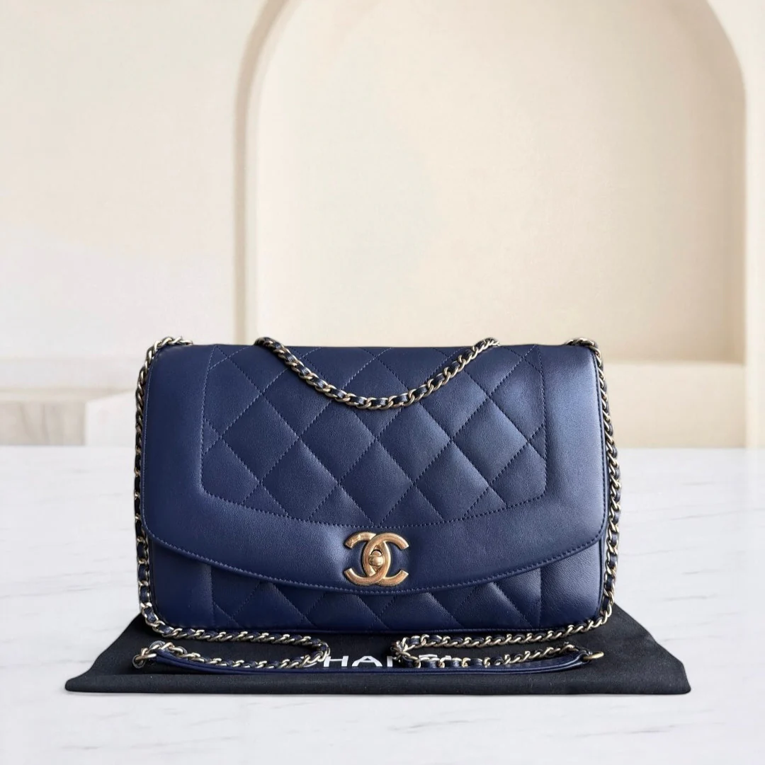 Blue quilted handbag with gold chain and logo on a white surface