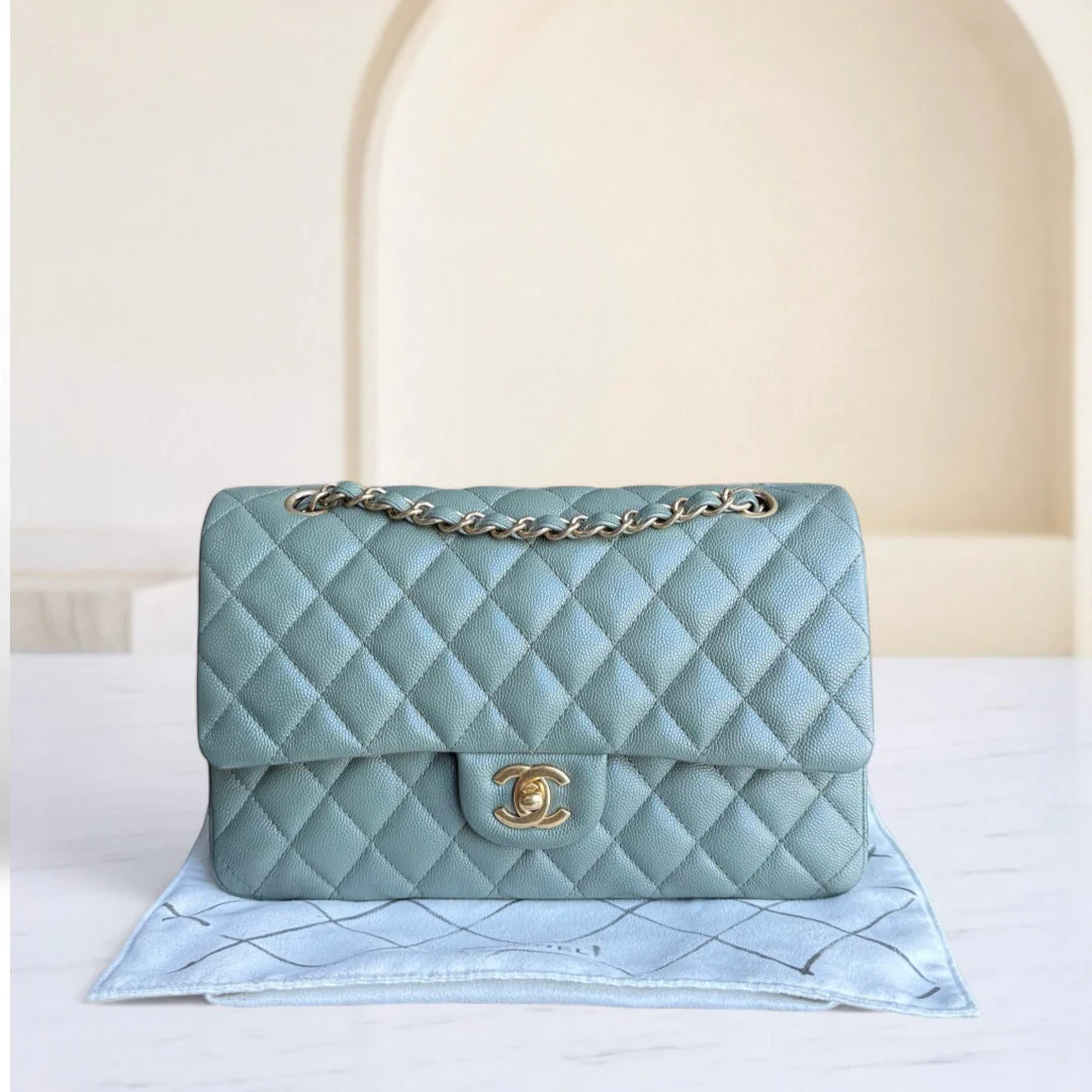 Light blue quilted handbag with gold chain and clasp on a light background