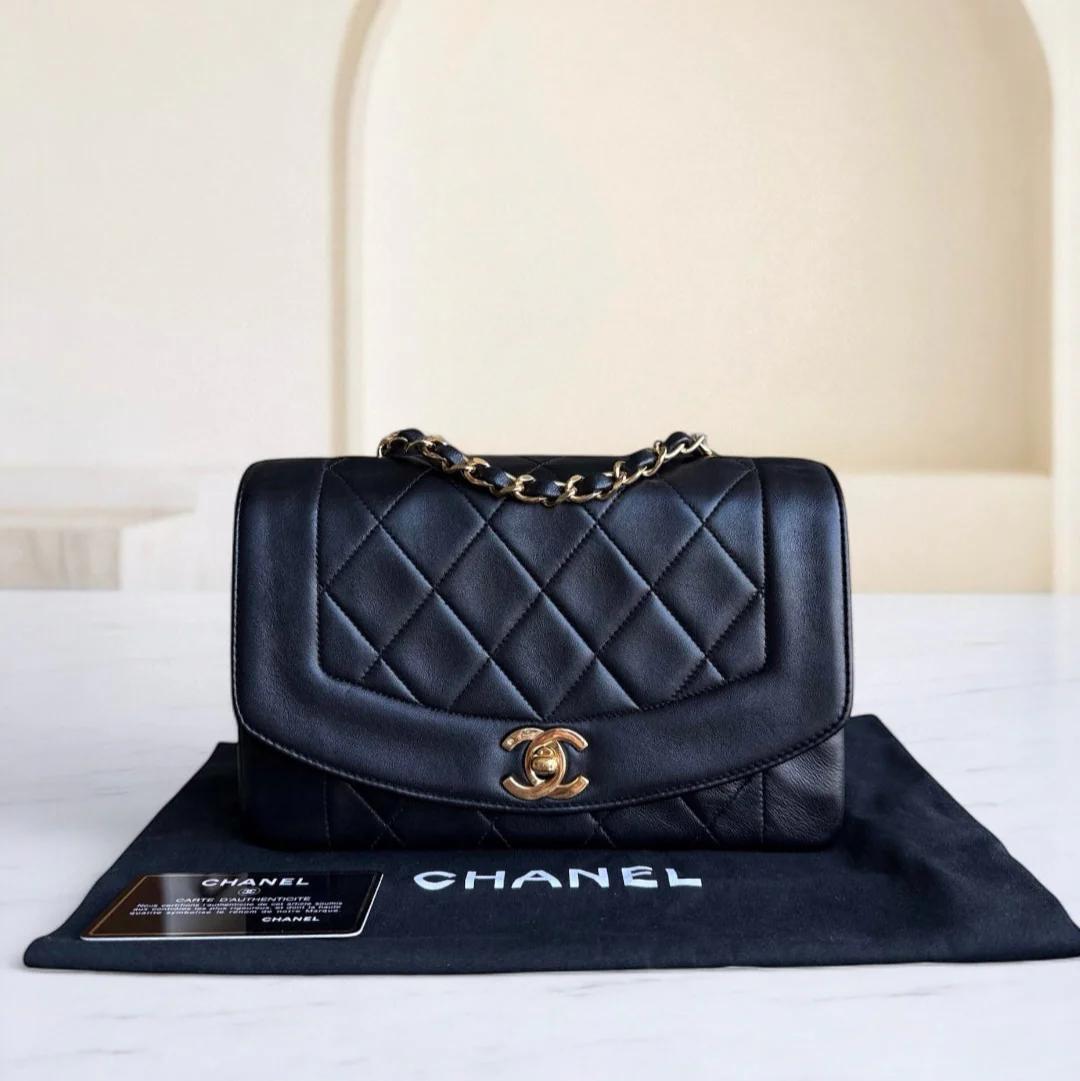 Black quilted Chanel handbag on a branded mat with a neutral background