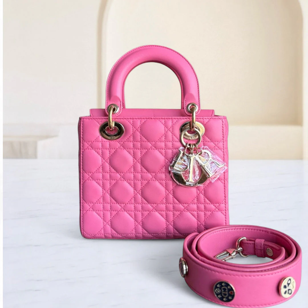 Pink quilted handbag with matching strap on a white background