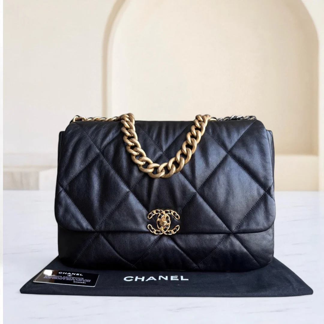 Black quilted Chanel handbag with gold chain on a white surface