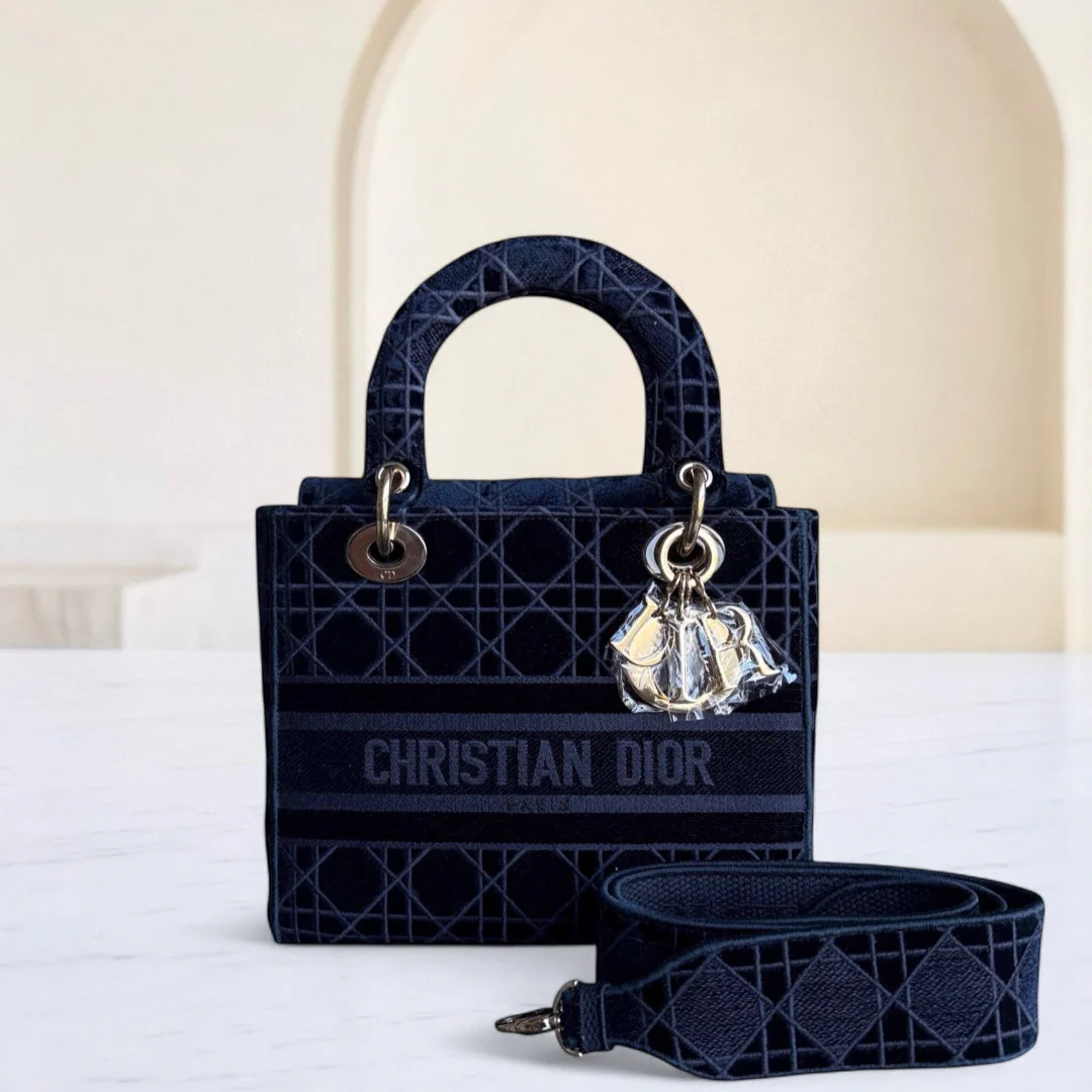 Black Dior handbag with strap on a white surface