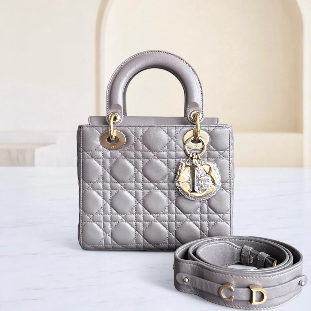 Silver quilted handbag with gold hardware on a white surface