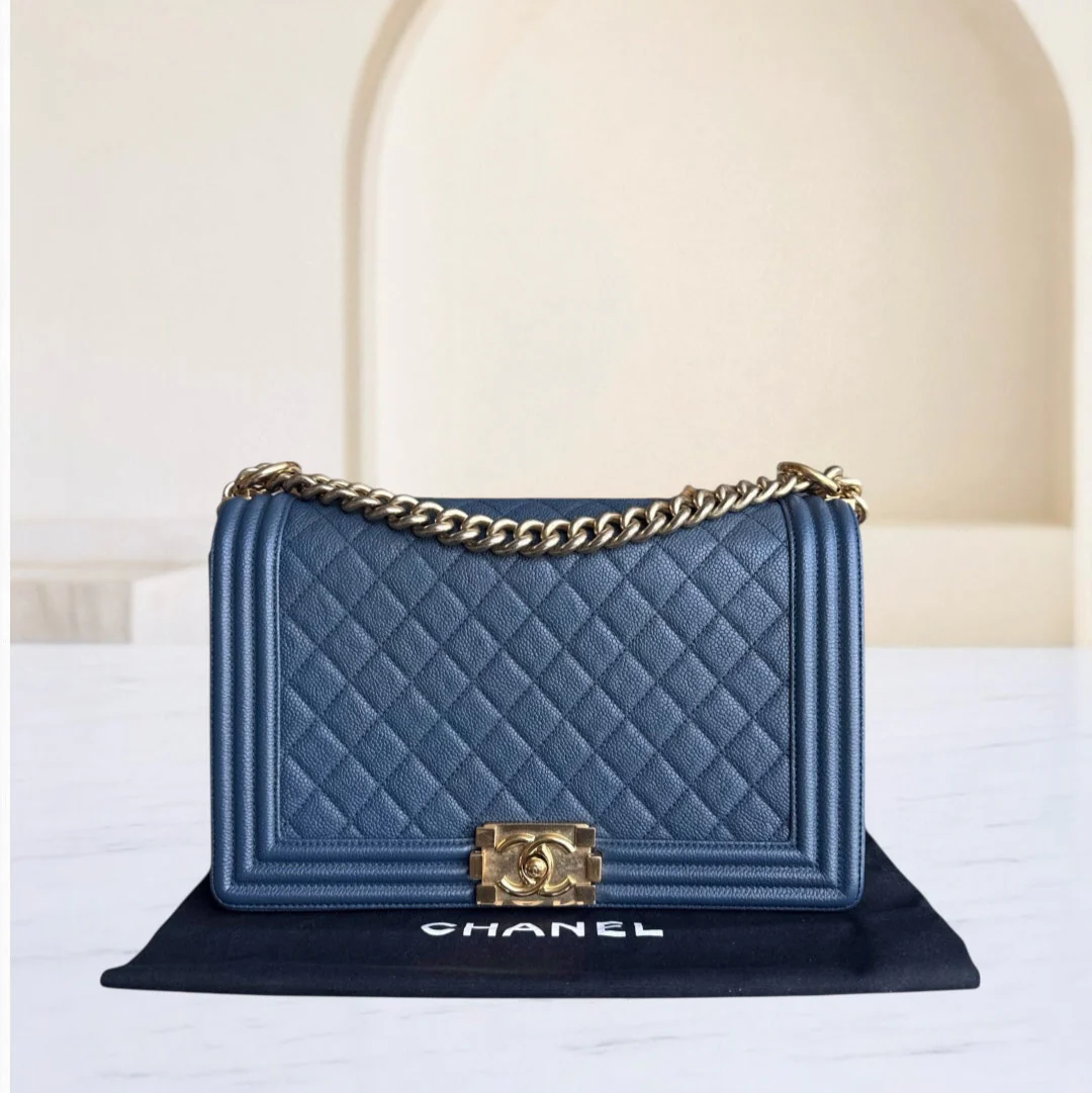 Blue quilted Chanel handbag with gold chain and clasp on a white surface.