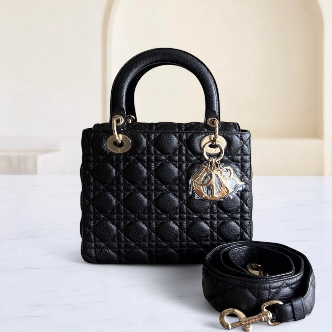 Black quilted handbag with gold hardware on a white surface