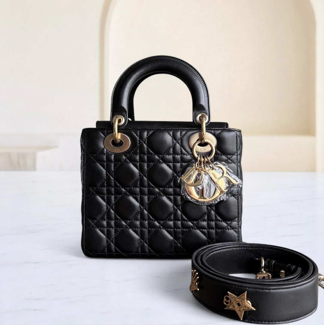 Black quilted handbag with gold hardware and a matching belt on a white surface.