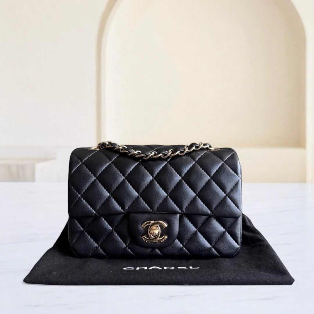 Black quilted Chanel handbag on a white surface with a blurred background