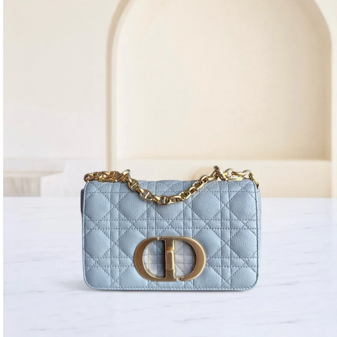 Light blue handbag with gold chain and clasp on a white surface