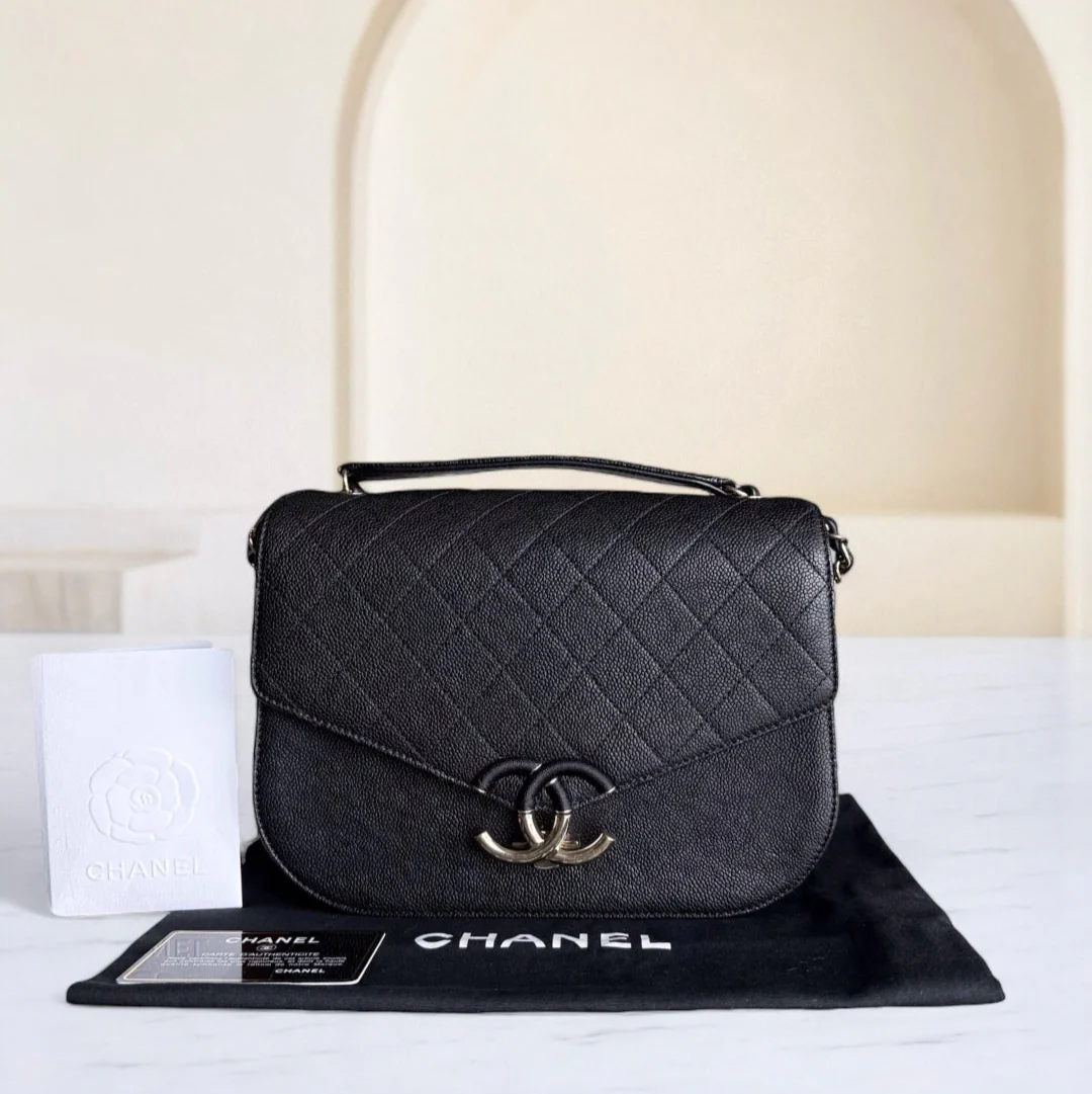 Black quilted Chanel handbag on a white surface with a beige background
