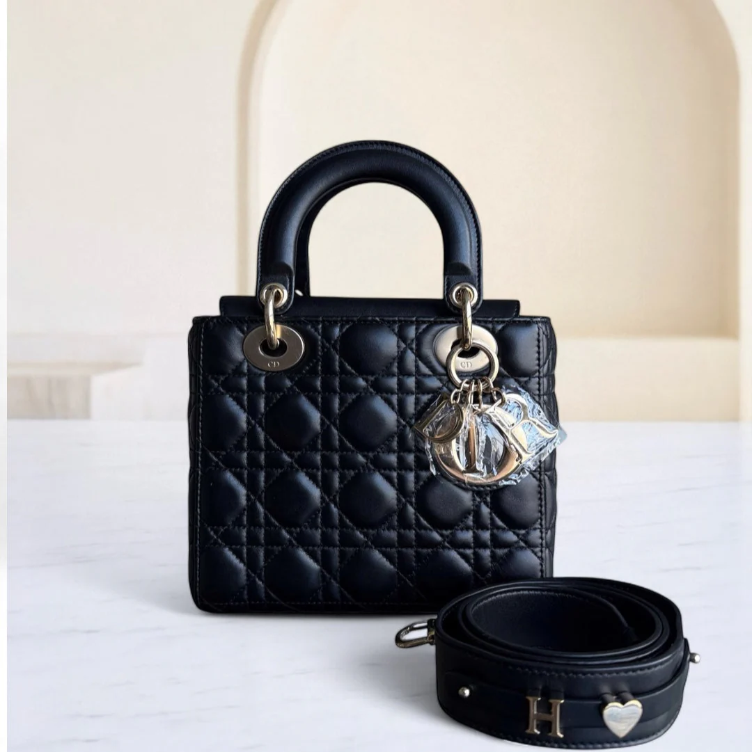 Black quilted handbag with a keychain and matching small pouch on a white surface.