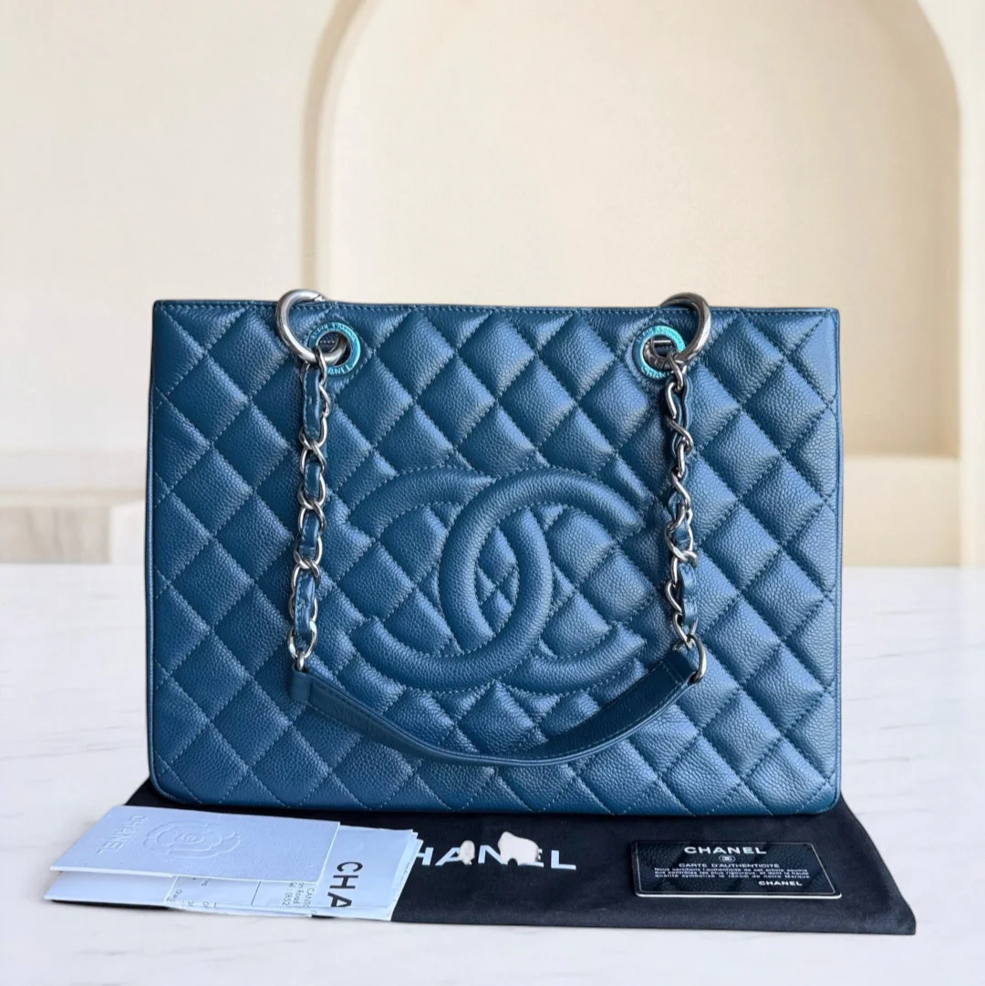 Blue quilted Chanel handbag on a white surface with a beige background