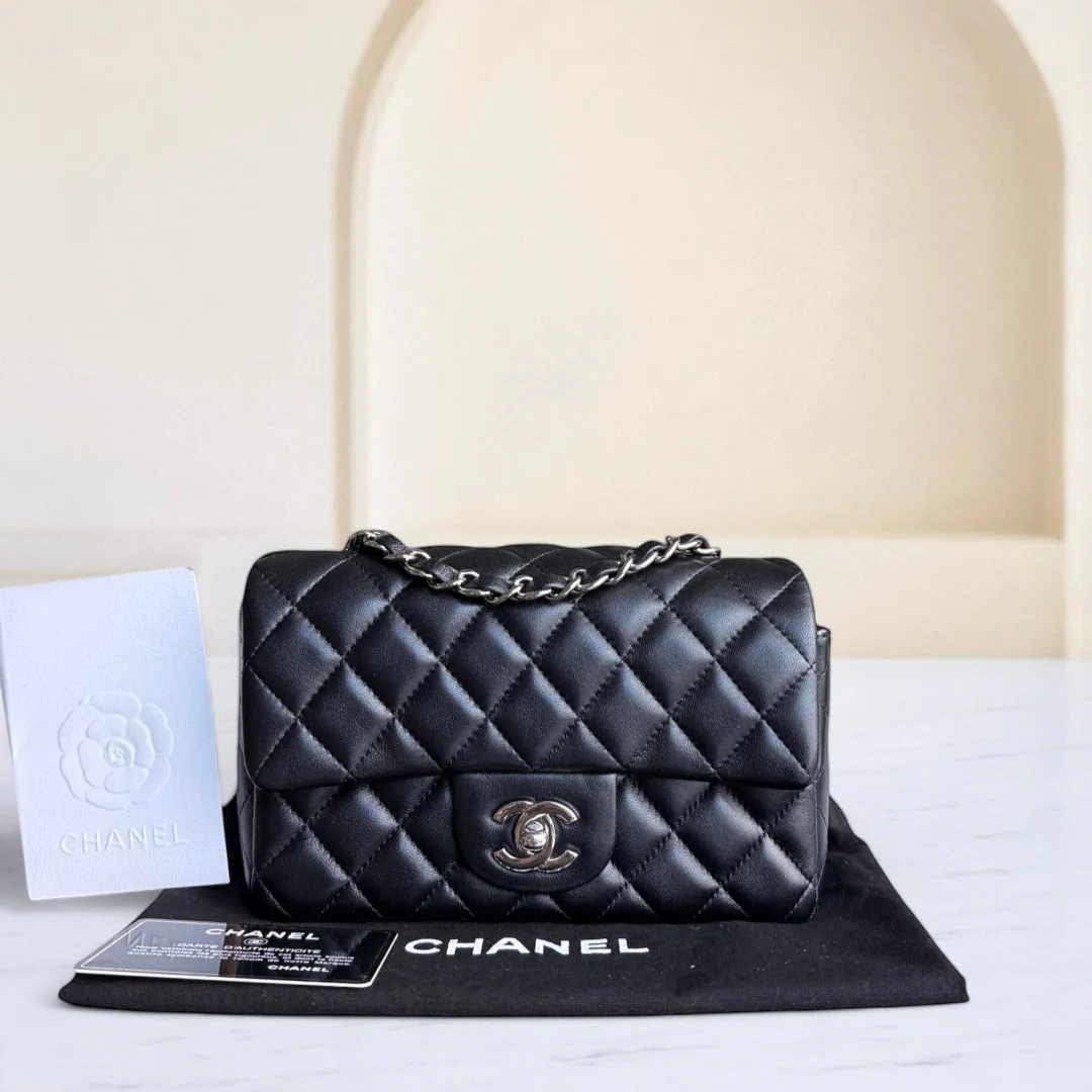 Black quilted Chanel handbag on a white surface with a beige background