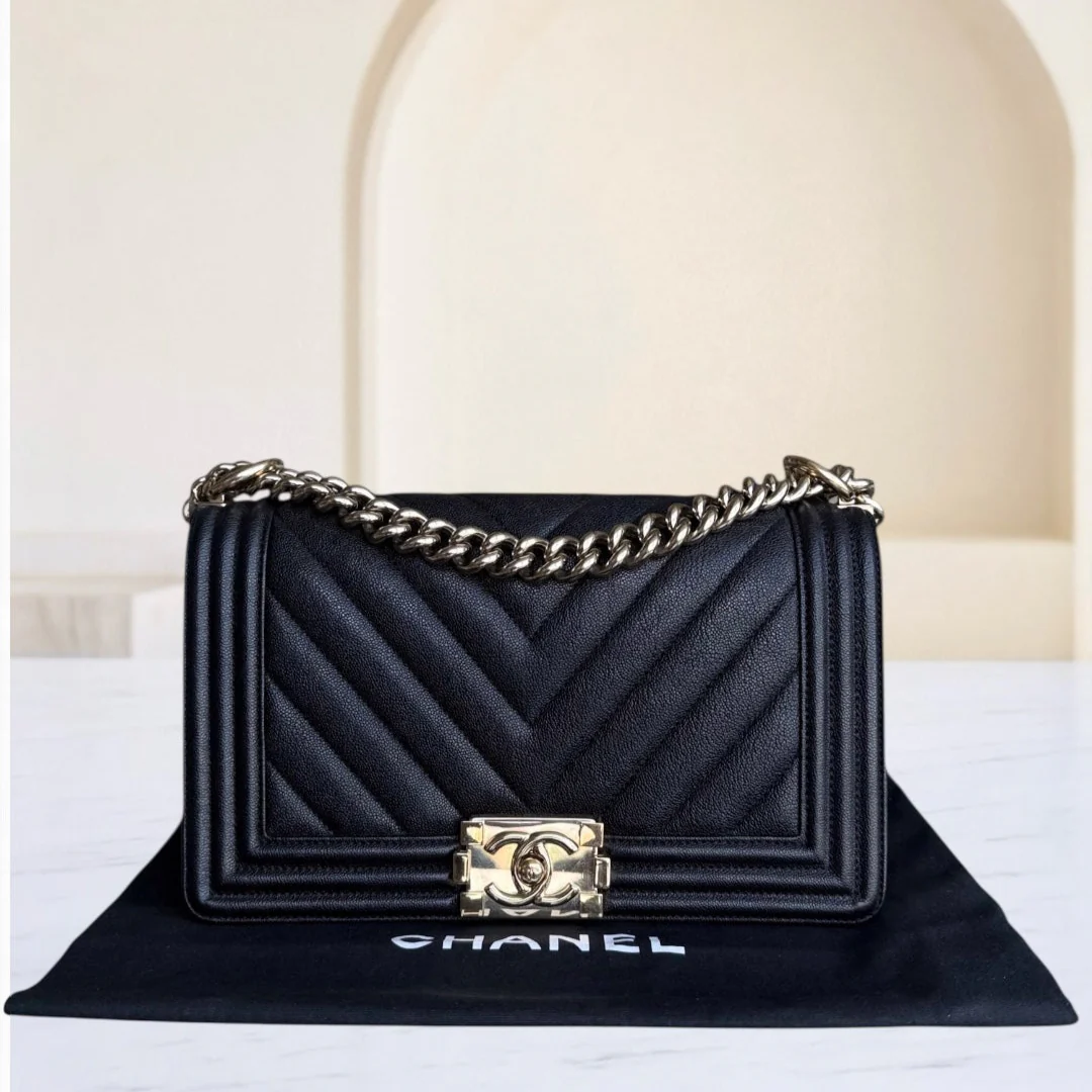 Black quilted handbag with gold chain and clasp on a white surface