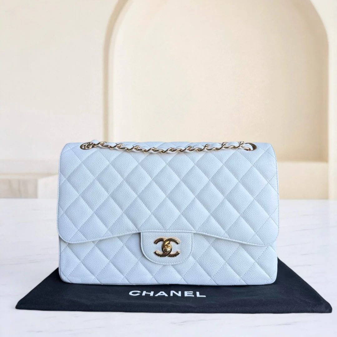 Light blue quilted Chanel handbag on a black mat with a beige background