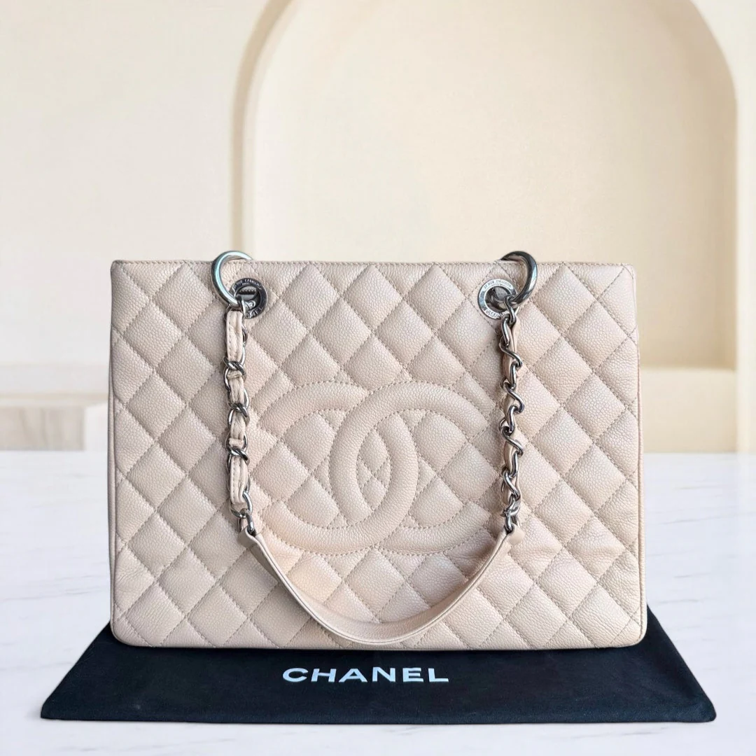 Chanel handbag on a black stand with a white background