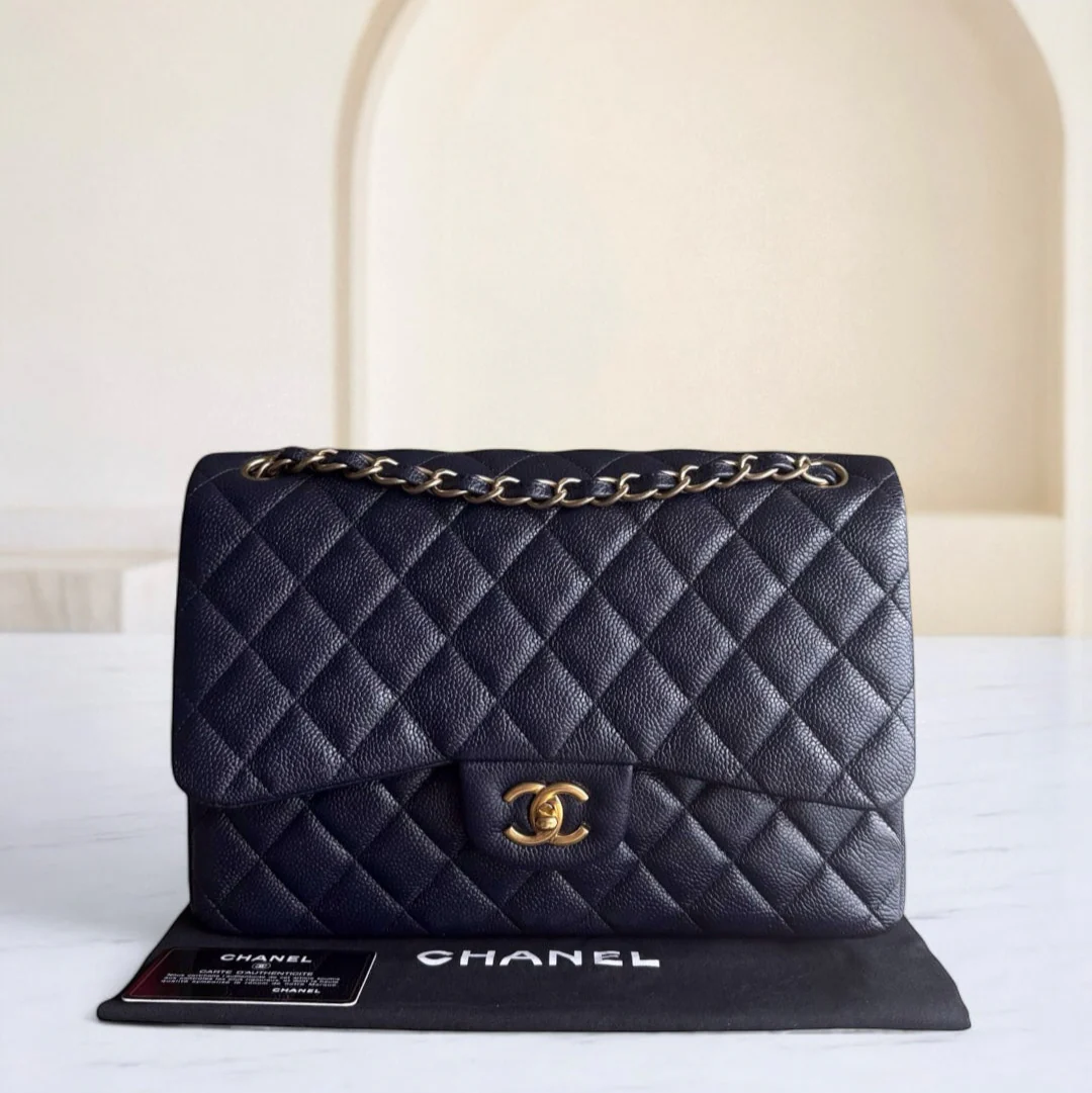 Black quilted Chanel handbag with gold chain on a white surface