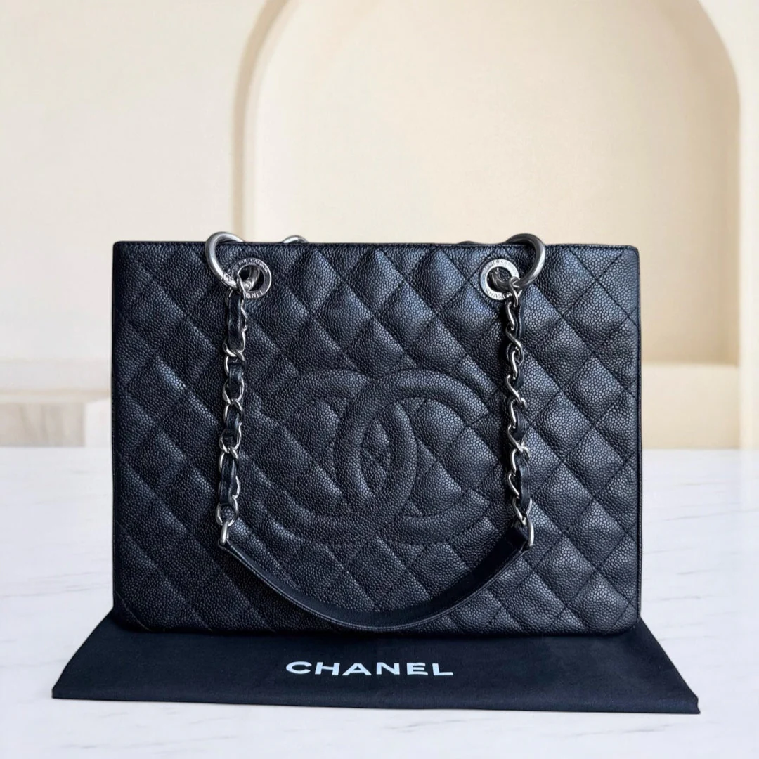 Black quilted Chanel handbag with chain detail on a white surface.