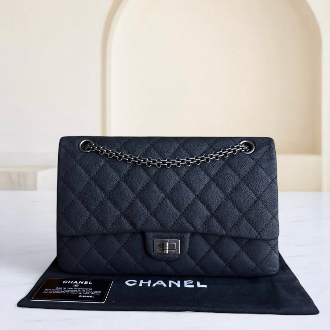 Black quilted Chanel handbag with chain strap on a white surface.