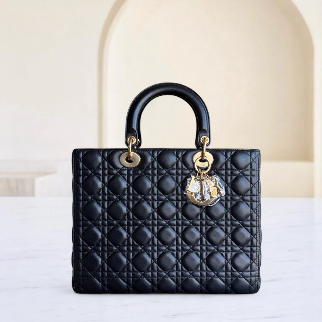 Black quilted handbag with gold accents on a white surface
