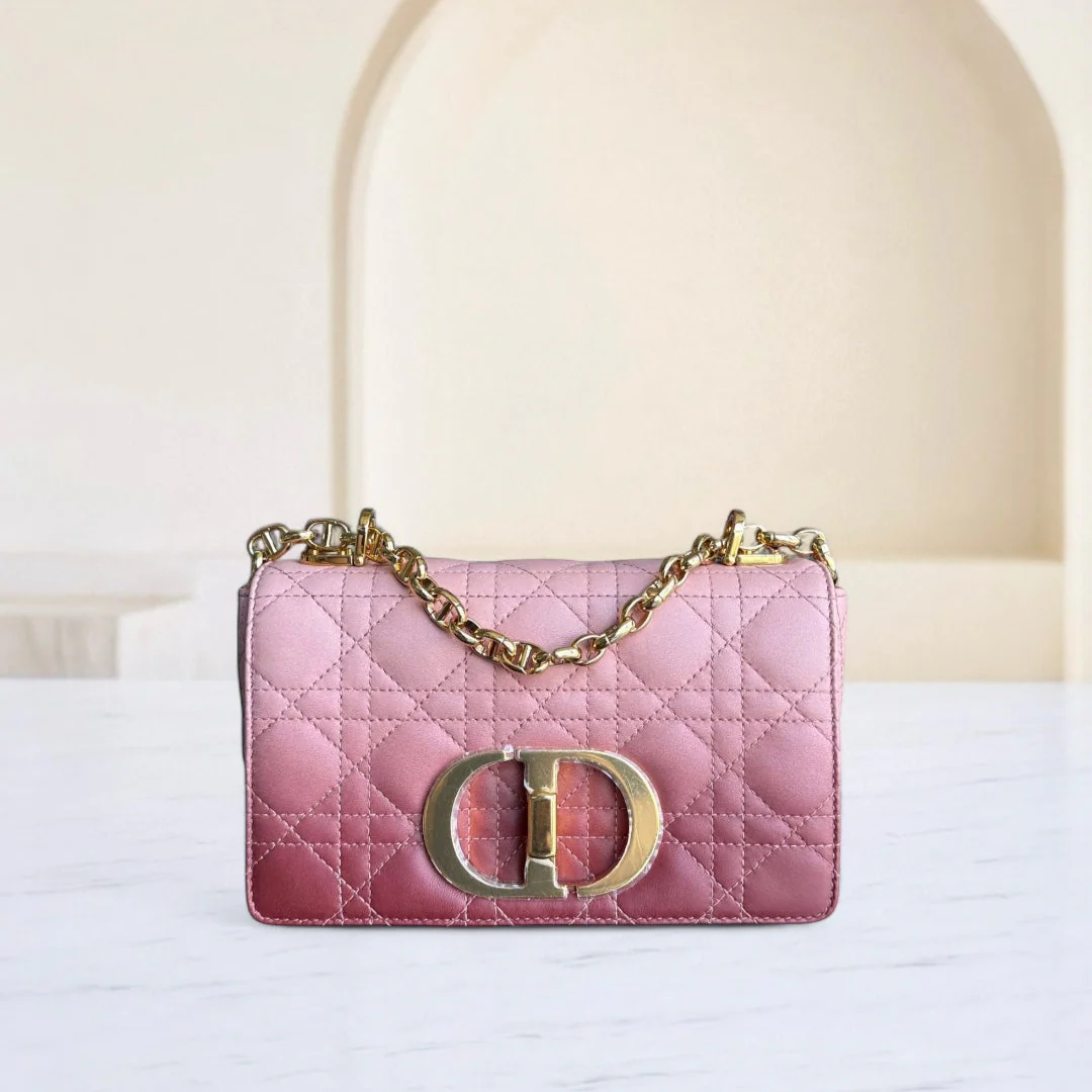 Pink handbag with gold chain and logo on a white surface