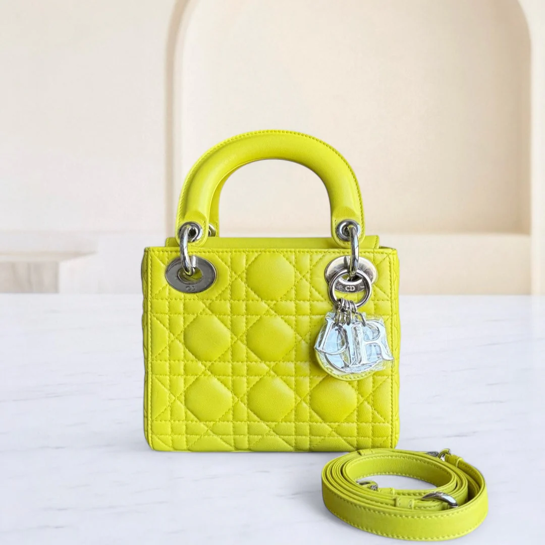 Yellow quilted handbag with silver hardware on a white surface