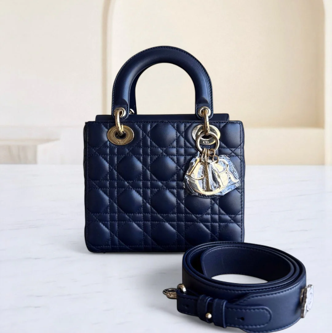 Navy blue quilted handbag with gold hardware on a white surface