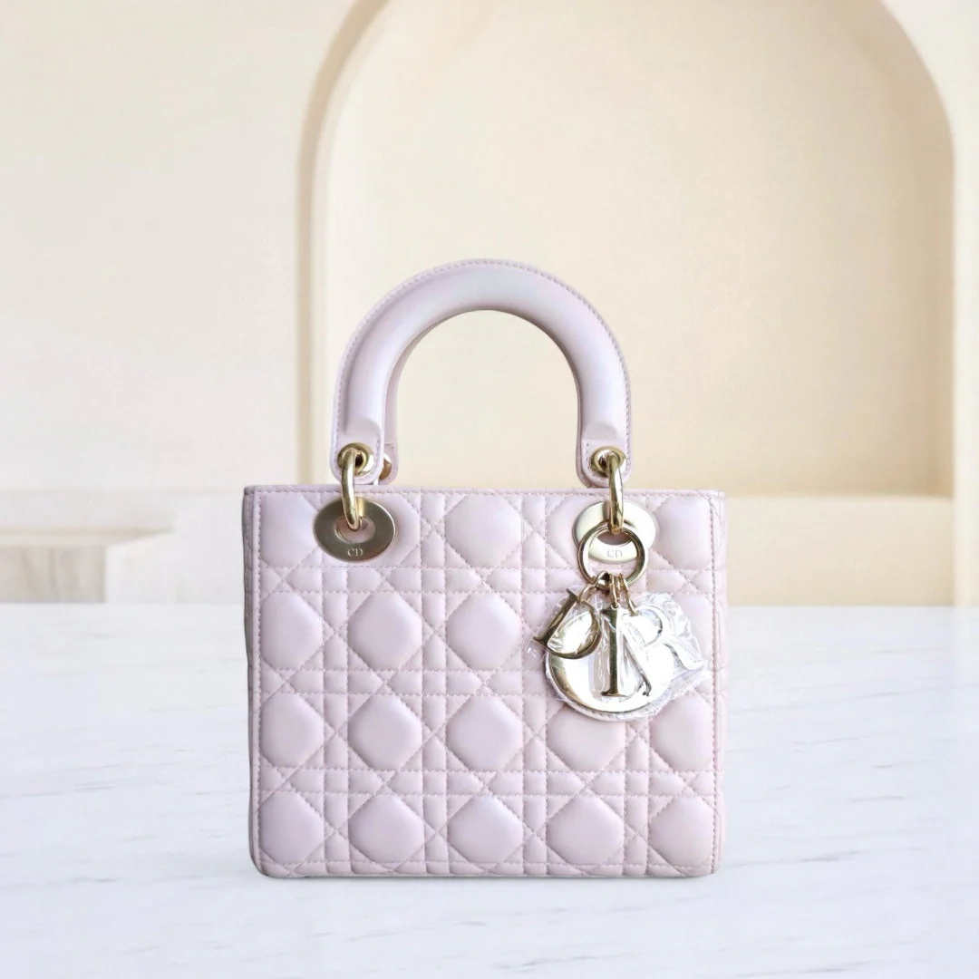 Pink quilted handbag with gold hardware on a white surface
