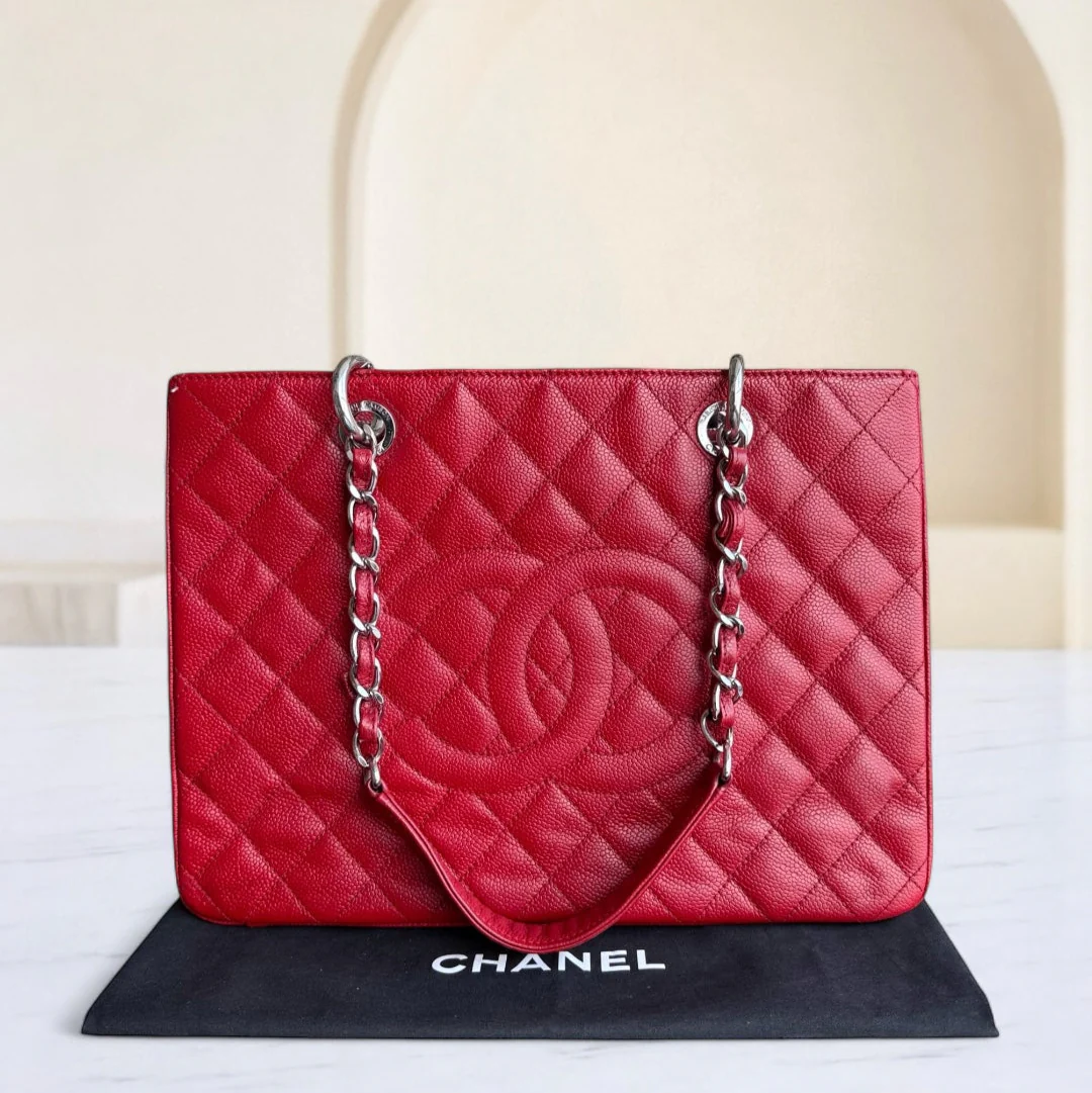 Red quilted Chanel handbag on a black stand with a beige background