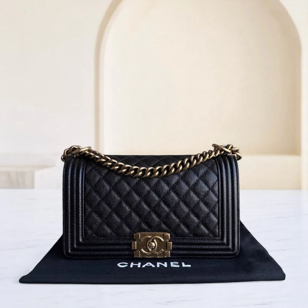 Black quilted Chanel handbag with gold chain on a white surface