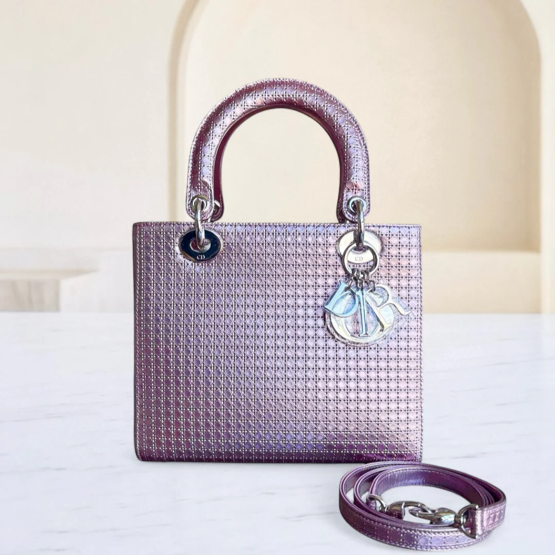 Purple handbag with a matching strap on a white surface