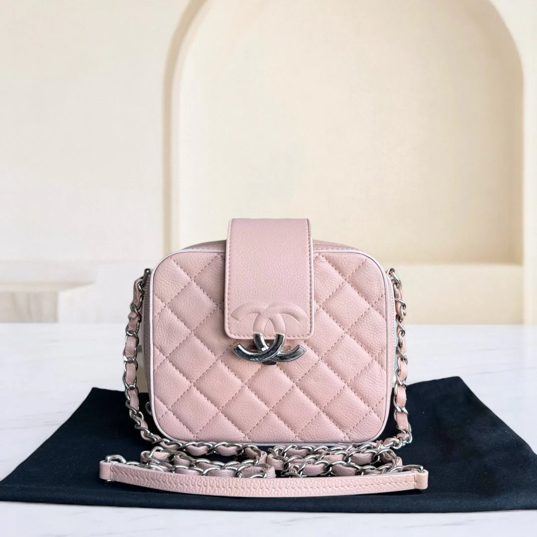 Pink quilted handbag with chain detail on a black mat