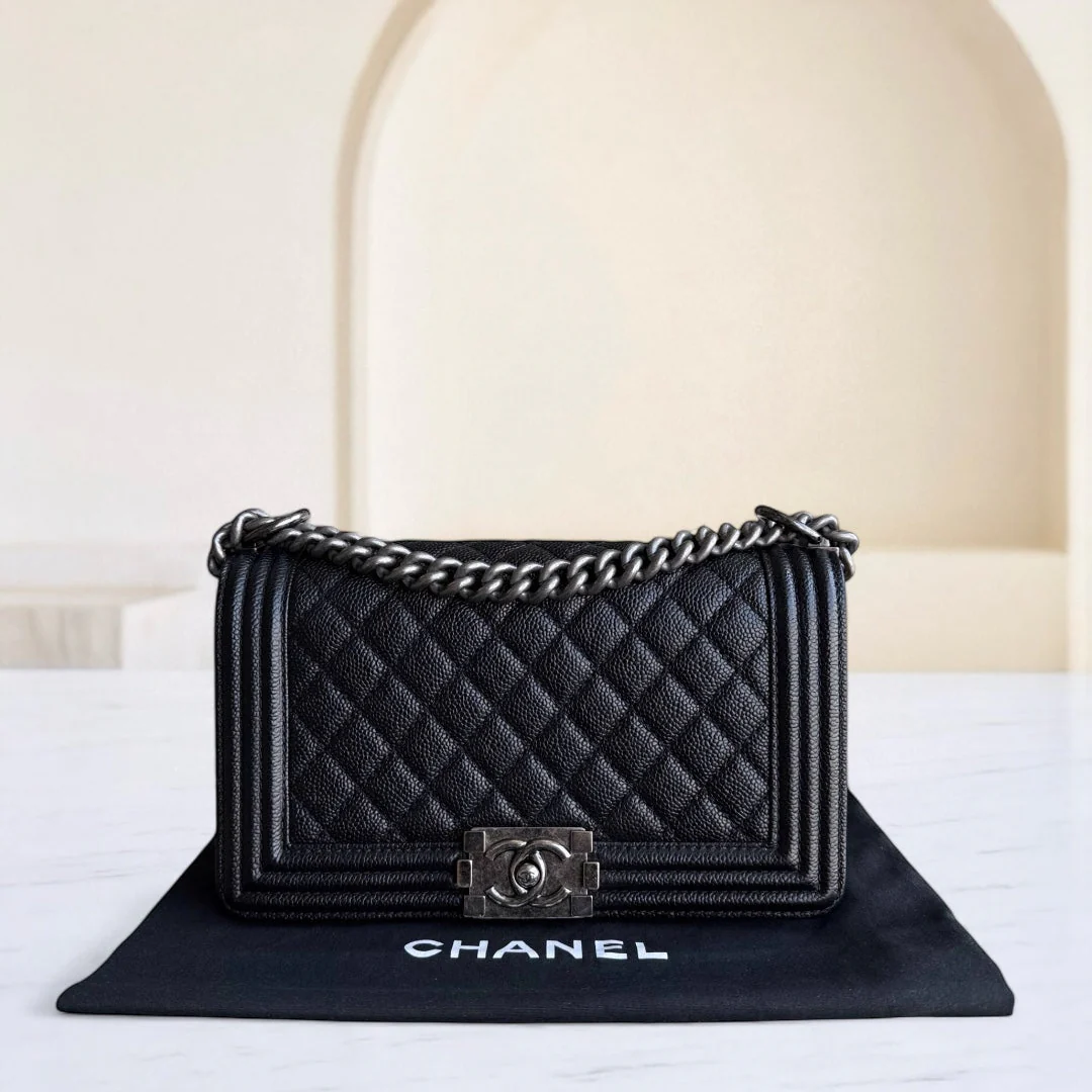 Black quilted Chanel handbag with chain strap on a black mat against a white background